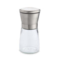 Clear glass spice jar with silver metal grinder lid on a white background
